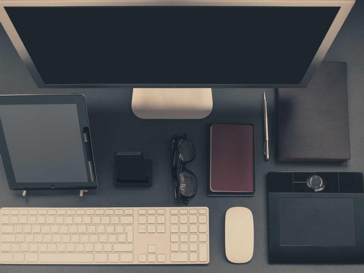 Escritorio de trabajo con computador y accesorios, visto desde arriba